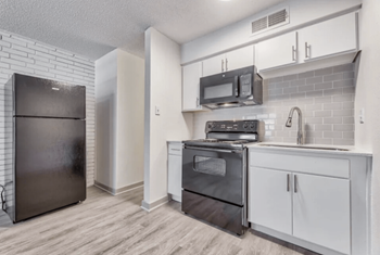 A kitchen with white cabinets and stainless steel appliances and a refrigerator